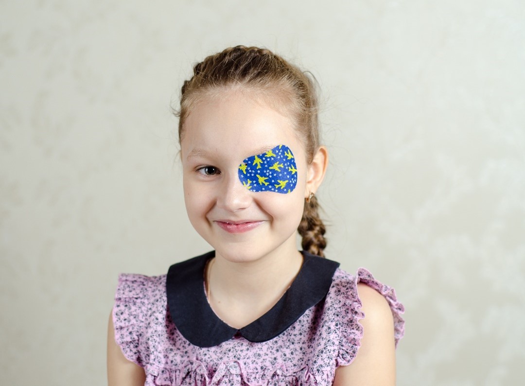 Bild eines Mädchens mit Okklusionstherapie (abgeklebtem Auge)